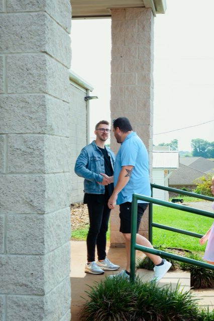 Two men talking outside under the walkway before the service