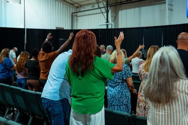 The congregation standing with hands raised during a song