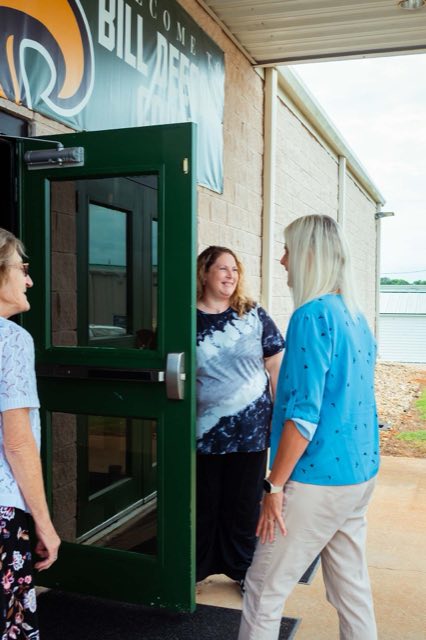 Women talking in the propped-open doorway as people arrive