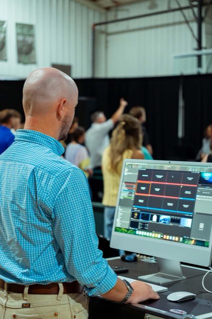 A volunteer running the slides from a computer at the back of the room