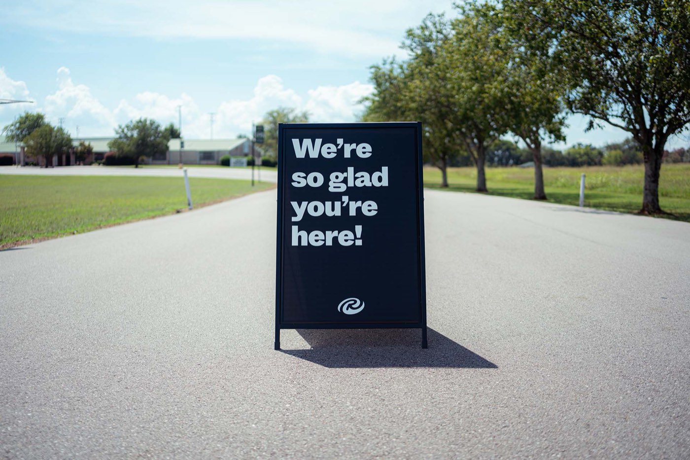 A sidewalk sign at the entrance reading, We are so glad you are here