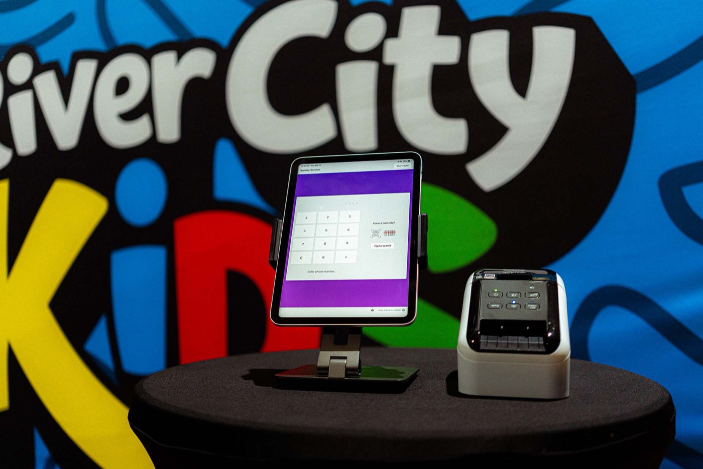 The check-in tablet and name-tag printer at the River City Kids station